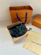 Dark blue monogram belt with green buckle and textured leather strap