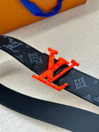 Louis Vuitton belt closeup: dark monogram strap with red LV buckle detail