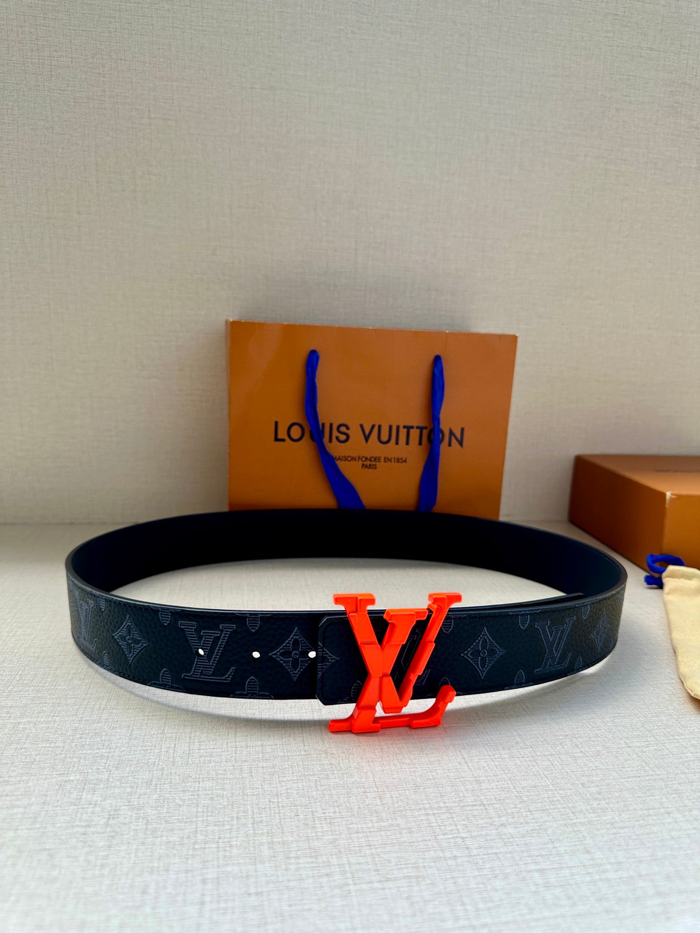 Louis Vuitton leather belt with dark monogram strap and red LV buckle