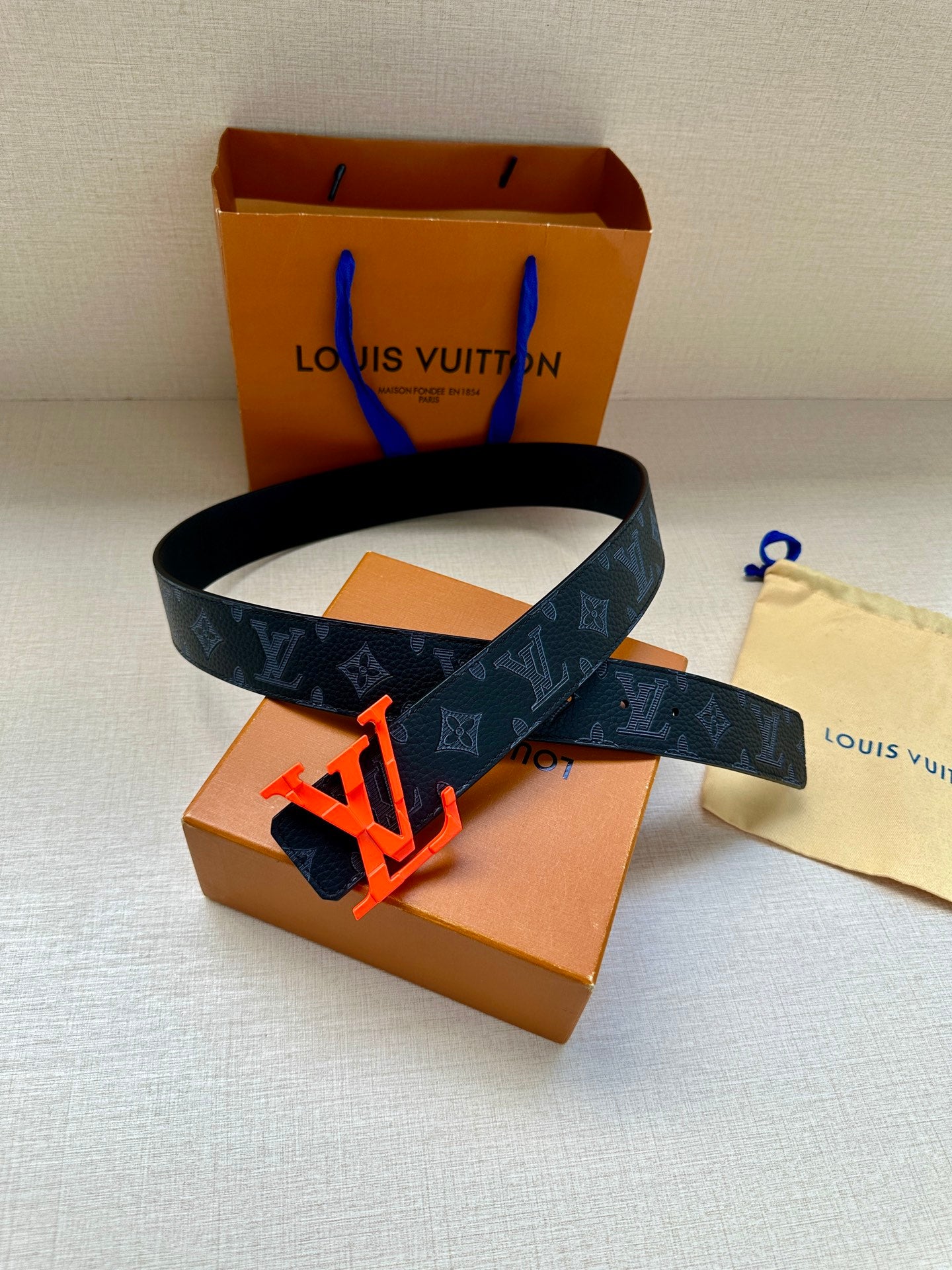 Louis Vuitton belt with dark monogram strap and red LV buckle, adjustable holes