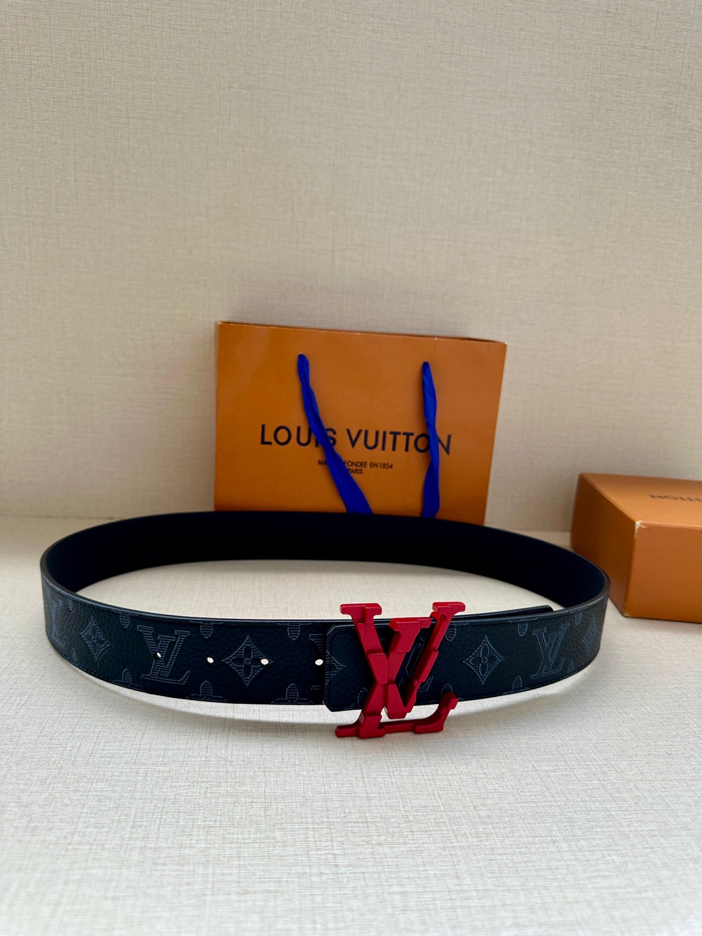 Louis Vuitton belt with dark monogram strap, red LV buckle centerpiece, blue lining