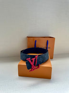 Louis Vuitton belt with dark monogram strap and red V emblem buckle on box