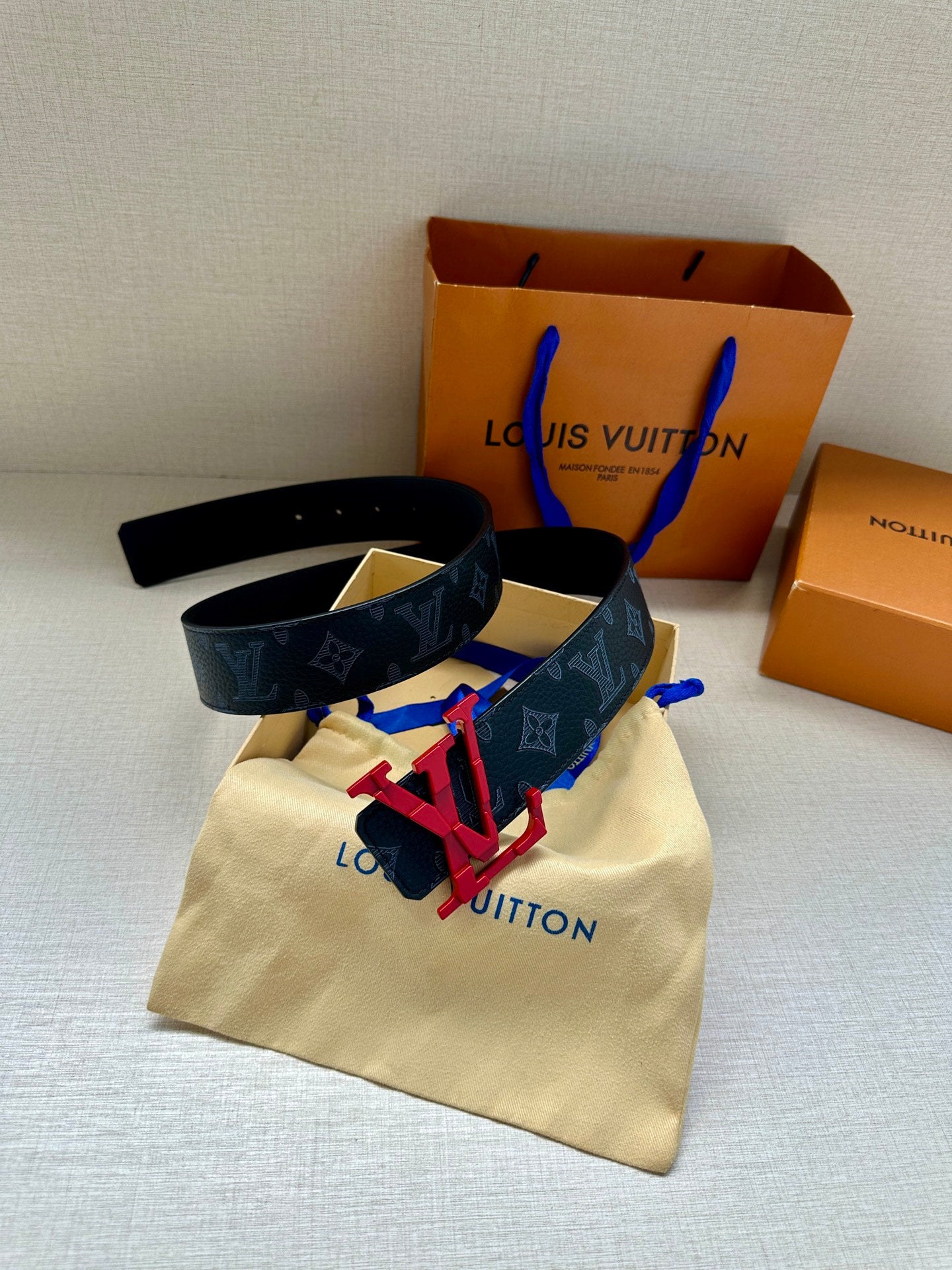 Louis Vuitton belt with dark monogram strap and red buckle hardware, dust bag included