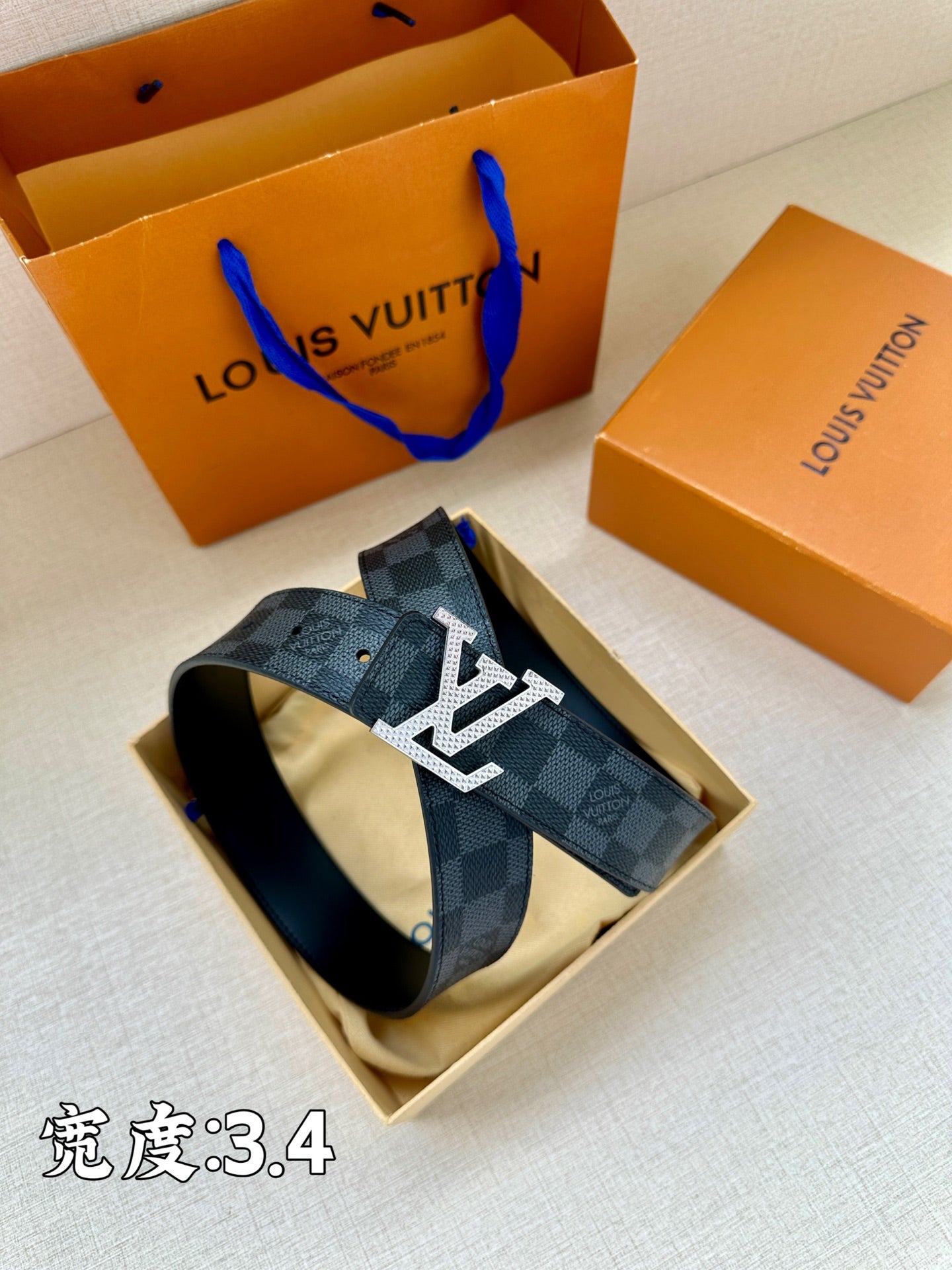 Checked belt in open box with LV buckle centered
