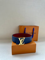 Louis Vuitton belt with navy blue strap and contrasting red underside, on boxes