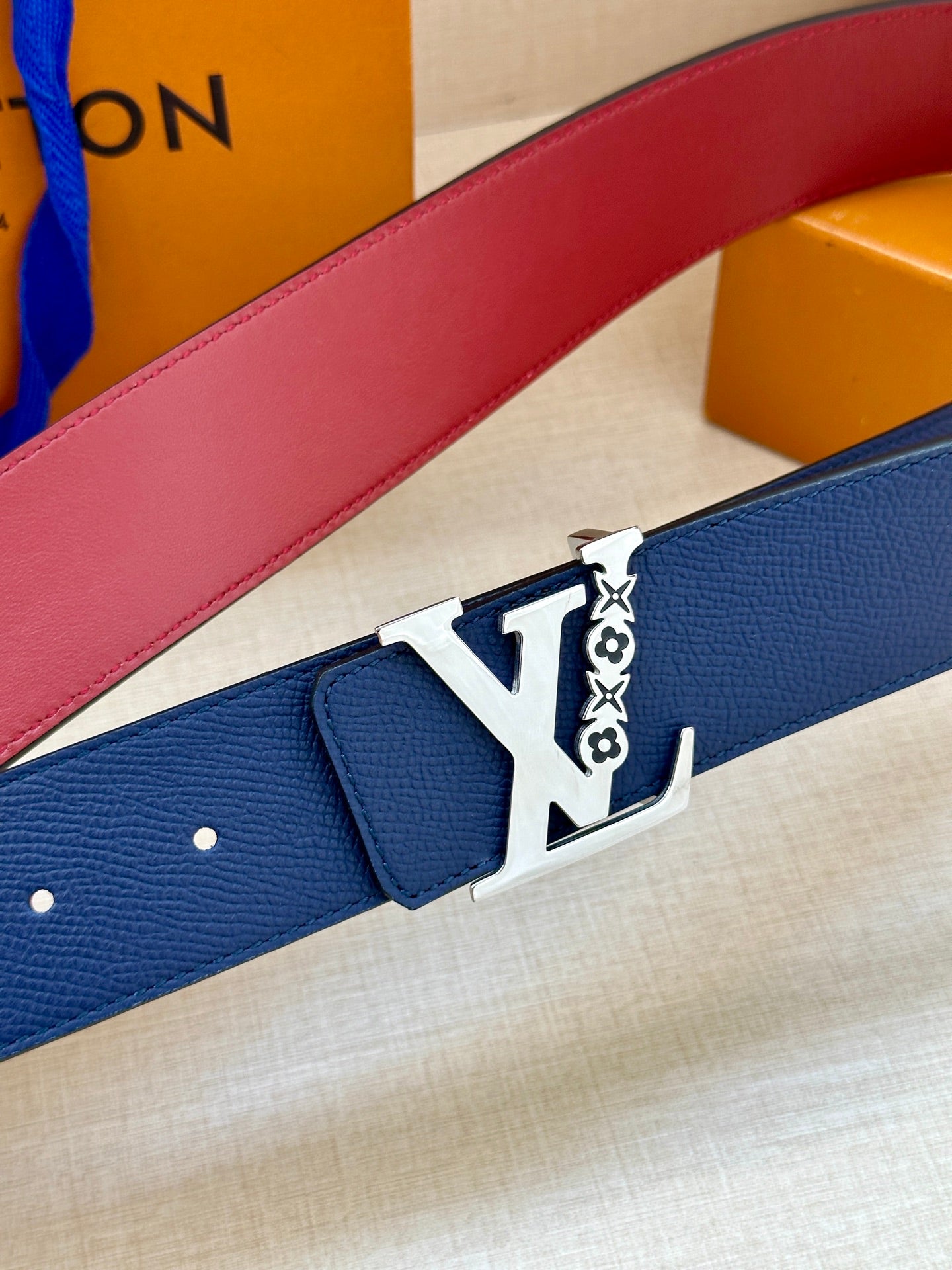 Louis Vuitton belt close-up with textured blue strap and silver LV buckle