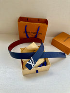 Louis Vuitton belt with navy blue strap and LV buckle, laid across gift boxes