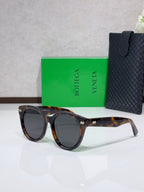 Dark tortoiseshell round sunglasses with black-tinted lenses and logo detail