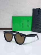 Black round sunglasses with brown-tinted lenses and small logo detail at bridge