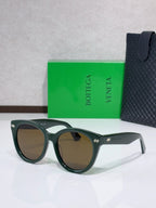 Olive-green round sunglasses with light-brown lenses and logo detail