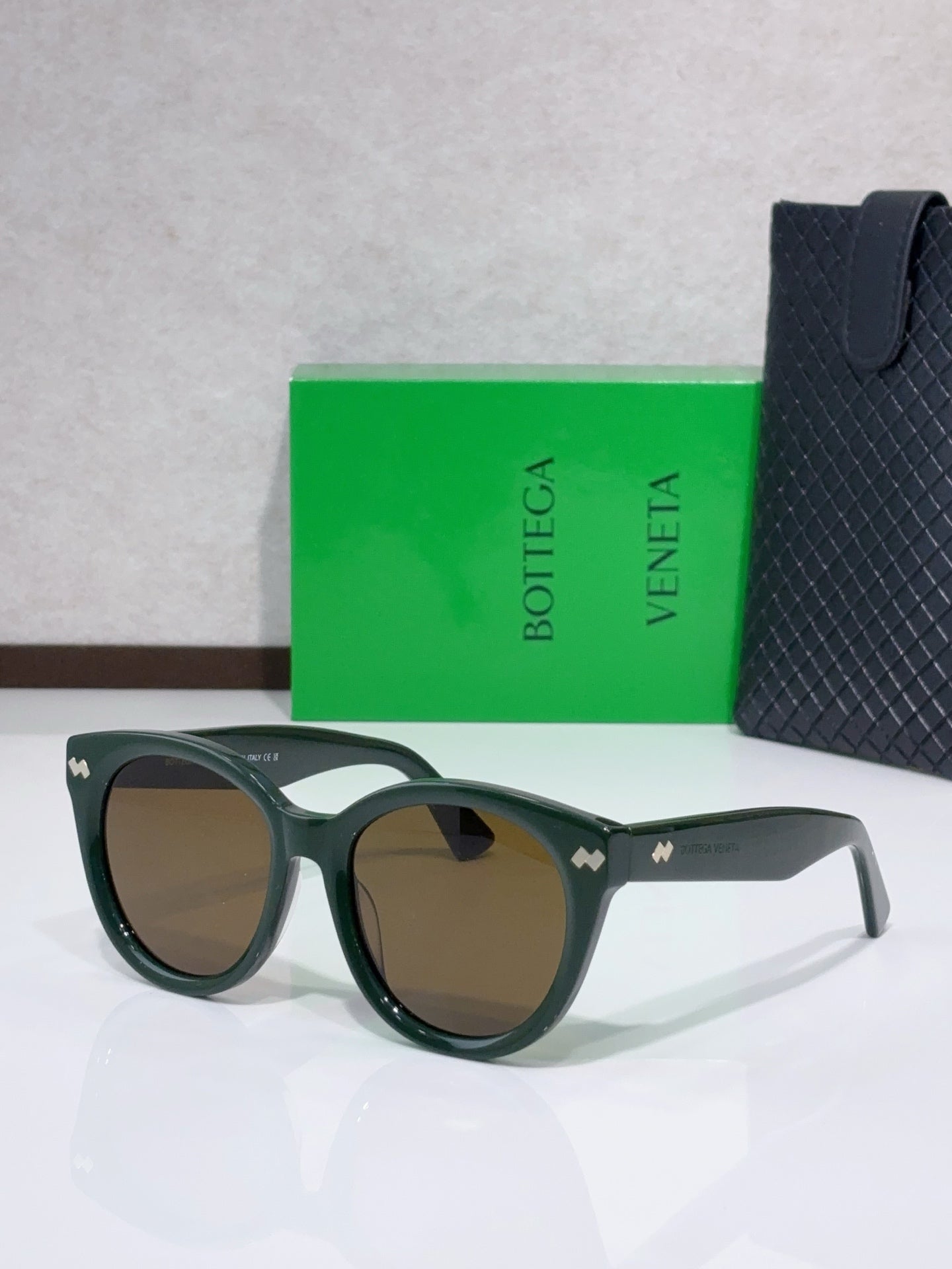 Olive-green round sunglasses with light-brown lenses and logo detail