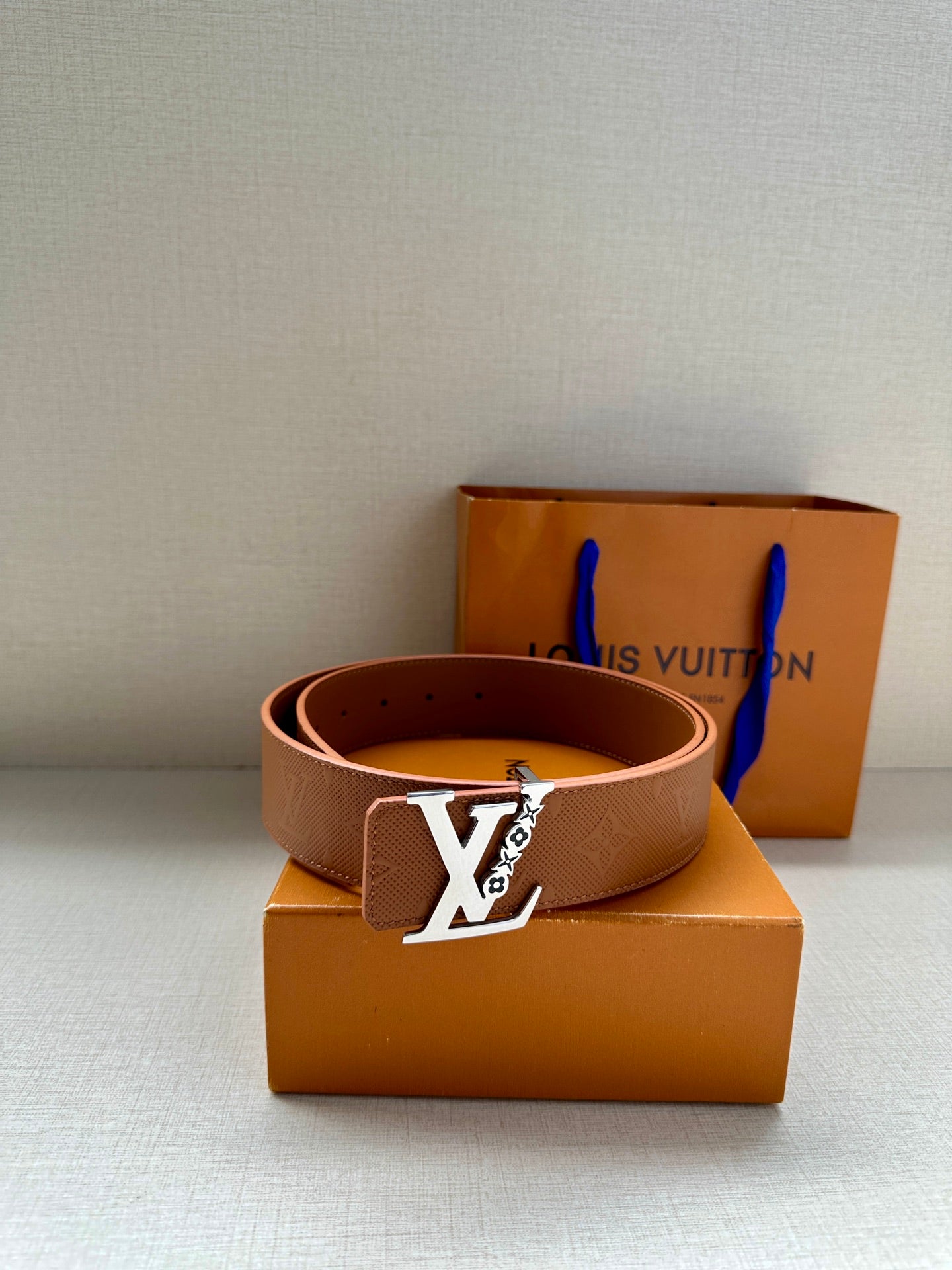 Louis Vuitton leather belt, tan/brown with LV gold buckle, coiled on box