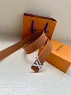 Louis Vuitton belt buckle on tan leather strap with embossed pattern and gold LV emblem