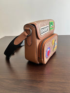 Coah bag crossbody, brown patterned exterior with Snoopy patch and shoulder strap