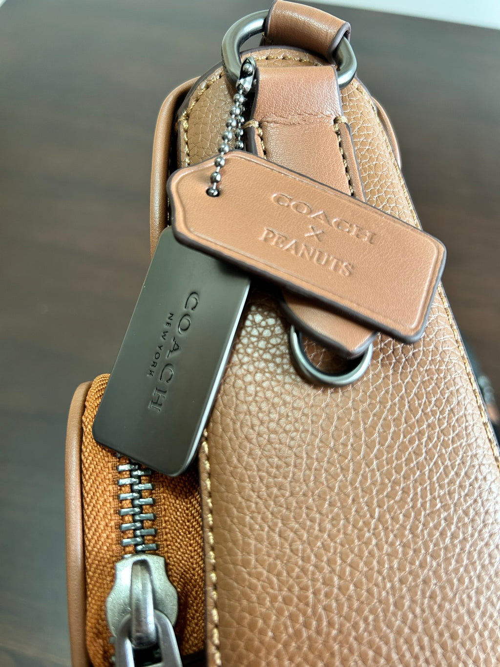 Coah bag with top handle, metal chain keychain, and leather pull tab