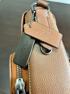 Coah bag with top handle, metal chain keychain, and leather pull tab