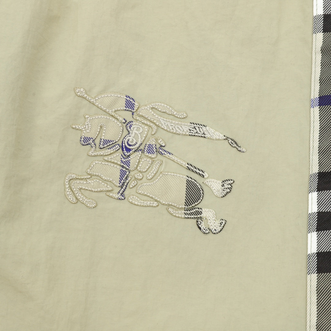 Beige pants with embroidered animal-style graphic on the front panel