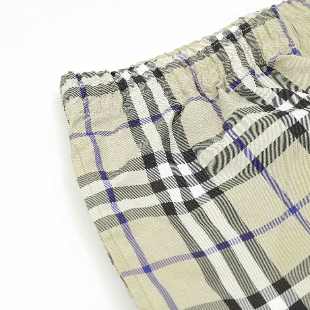 Plaid pants fabric at hem with elastic, beige, black, and blue check pattern