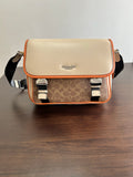 Beige crossbody bag with orange trim, flap top, and adjustable dark shoulder strap