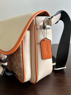 Beige crossbody bag side view with orange trim, key ring charm, and strap