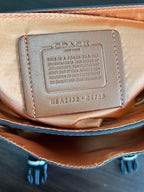 Leather interior tag on beige crossbody bag with embossed text and serial code