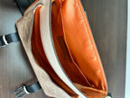 Interior of beige crossbody bag showing orange lining and inner compartments