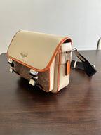 Beige crossbody bag with orange-trimmed flap and dark adjustable shoulder strap