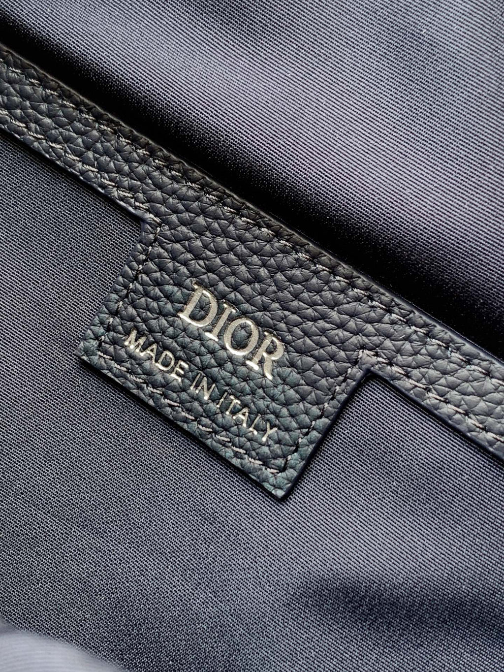 Dior men’s bag leather label with “Dior” and “Made in Italy” text