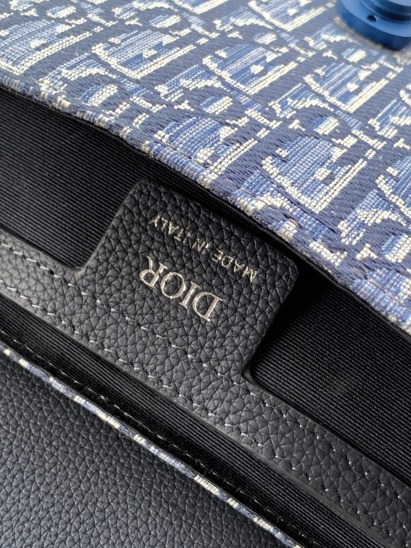 Black leather interior label with 'Dior' logo on blue monogram bag.