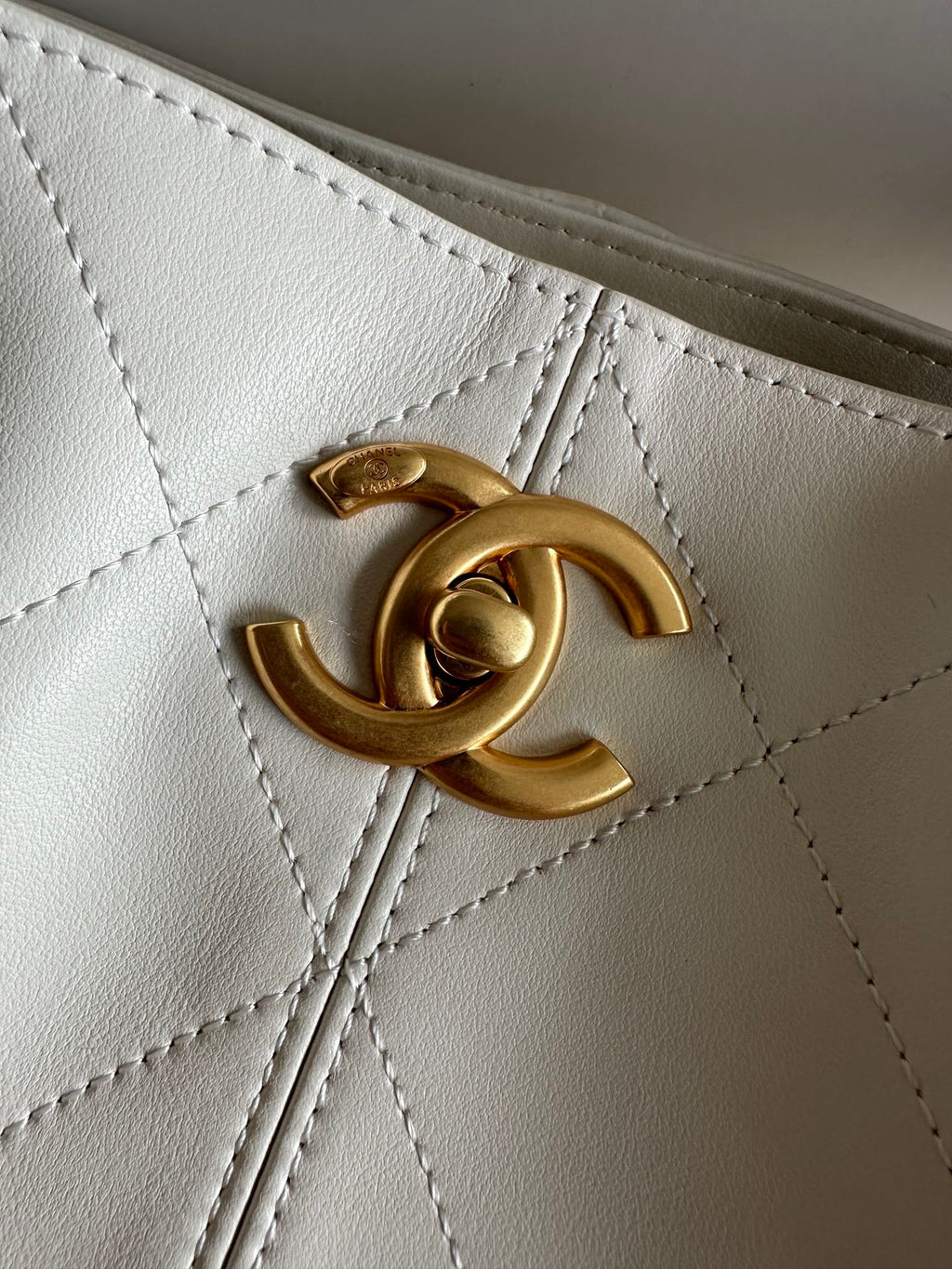 Gold Chanel CC logo detail on white quilted bag