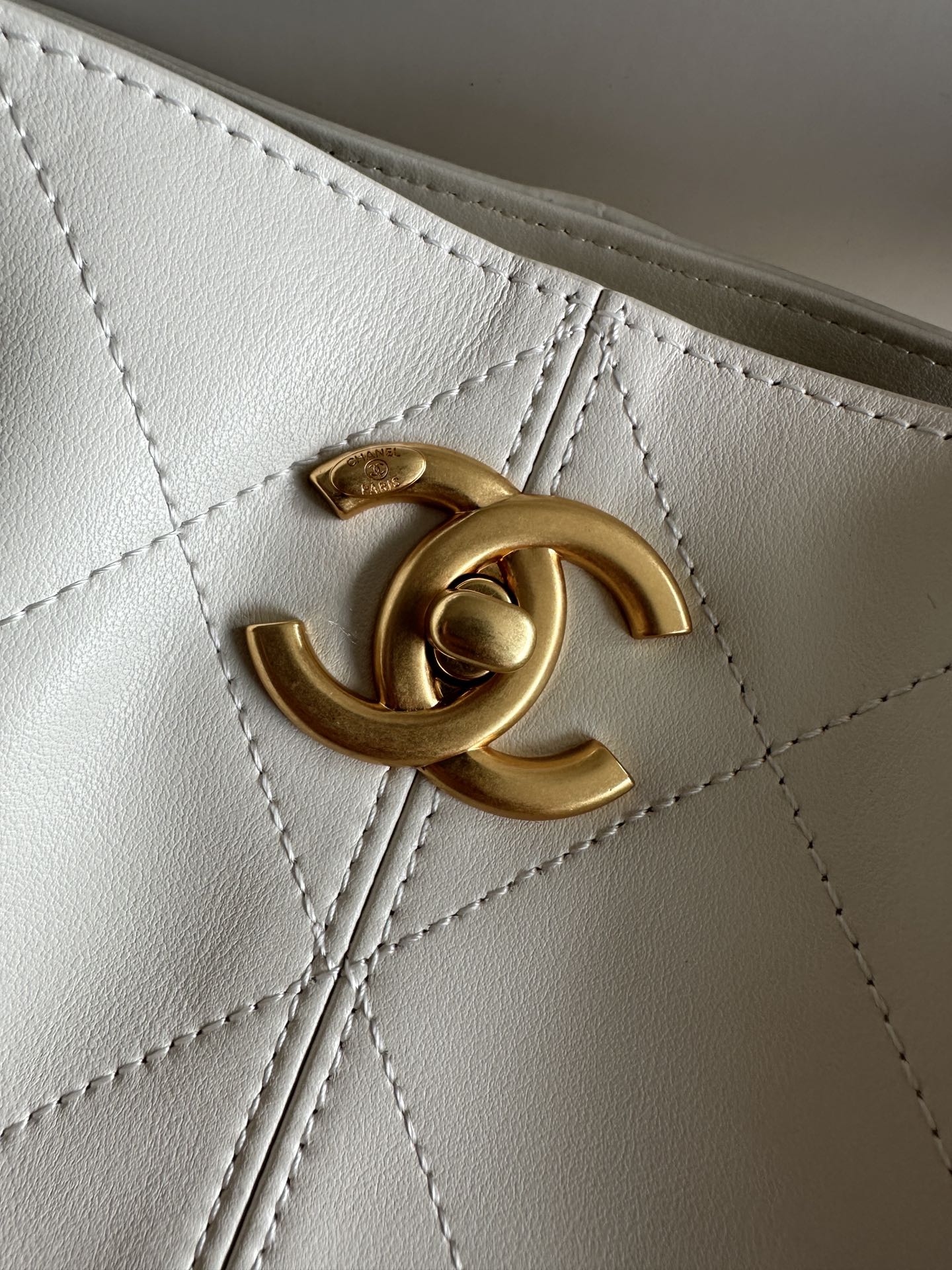 Gold Chanel CC logo detail on white quilted bag