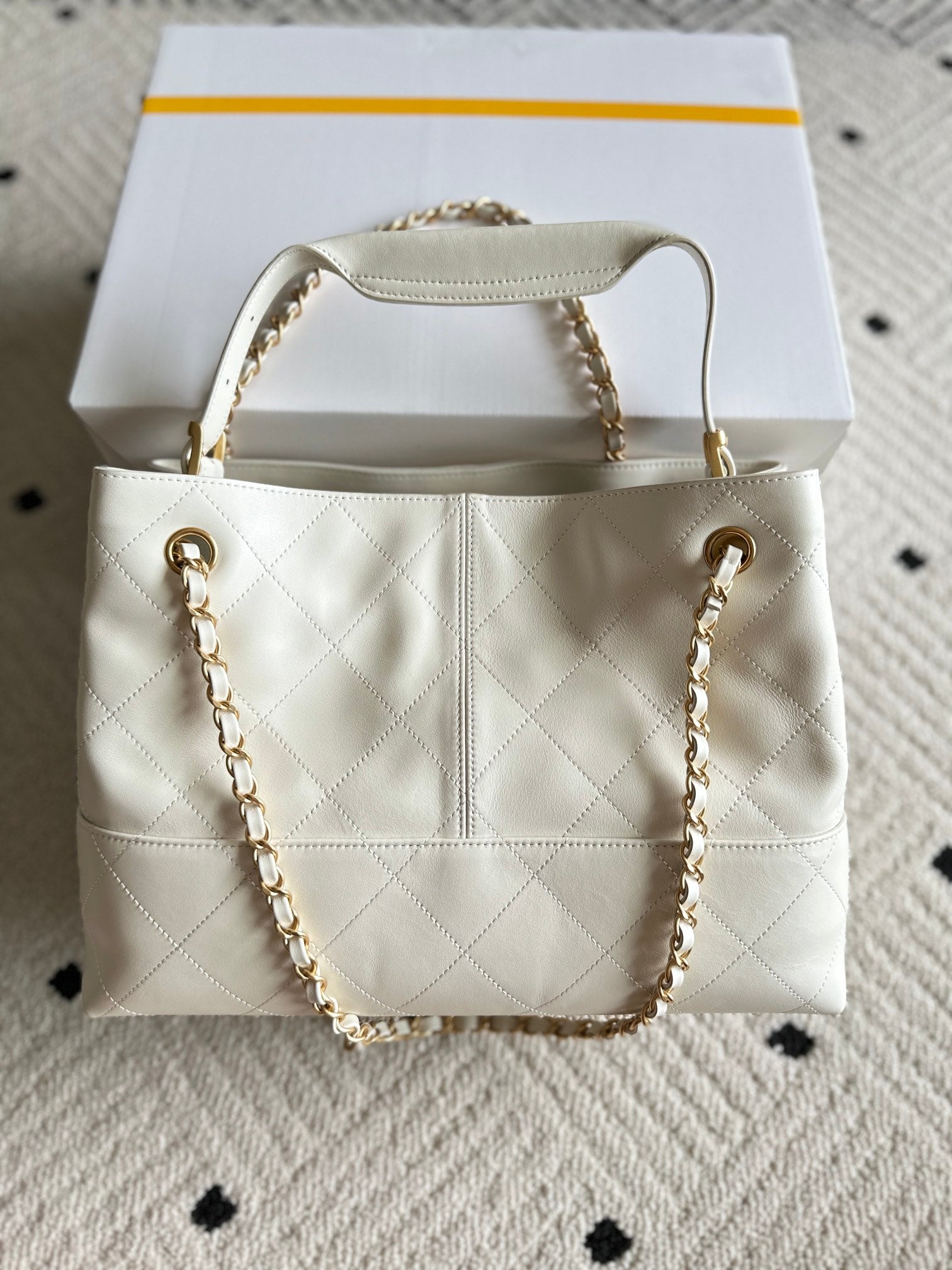 White quilted Chanel tote bag style with gold chain straps and CC front