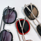 Assorted sunglasses on display: metal frames with dark lenses and colorful trim.