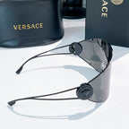 Shield sunglasses with dark gray mirrored lenses, black temple hinges, round logo medallion.