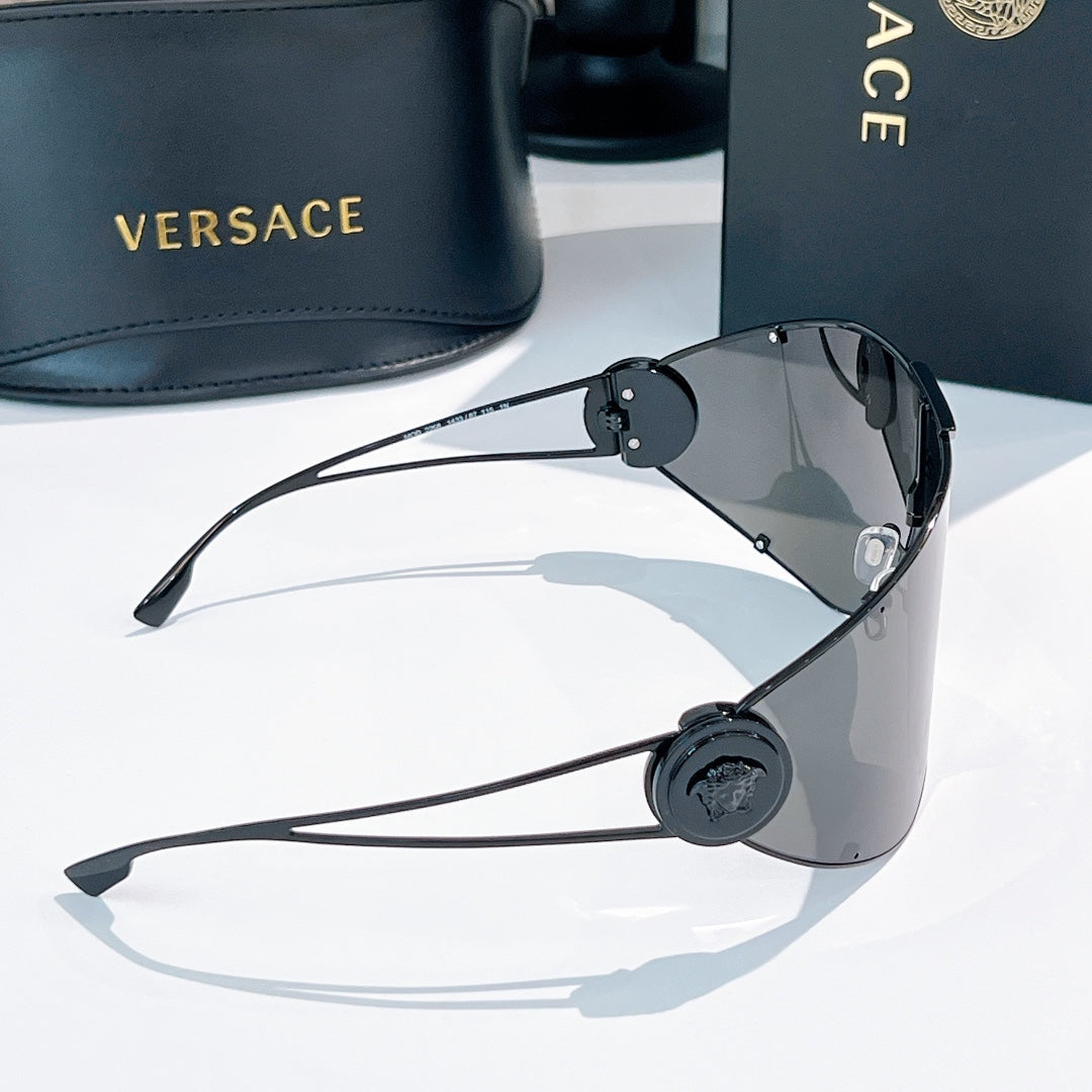 Shield sunglasses with dark gray mirrored lenses, black temple hinges, round logo medallion.
