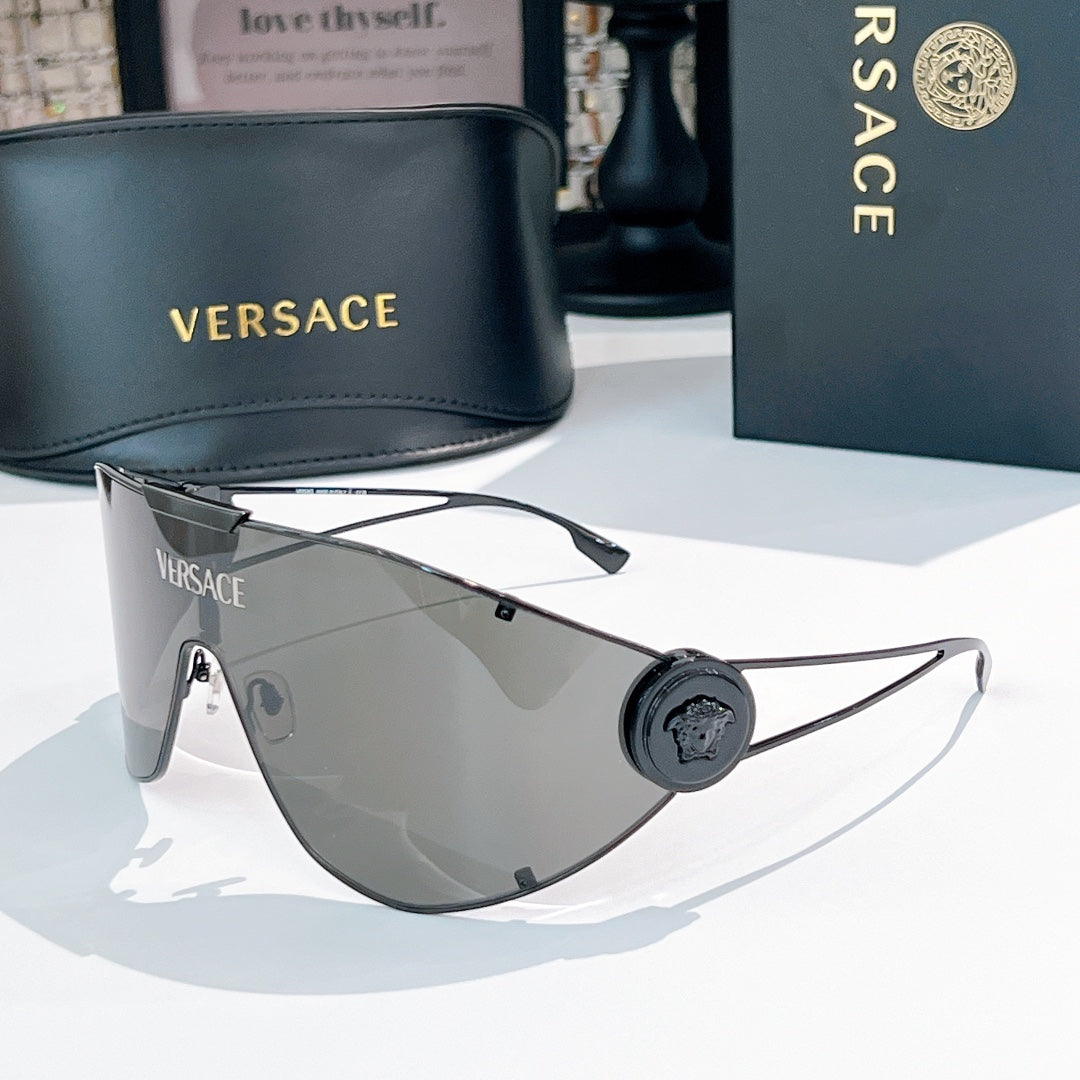 Sunglasses with gold-tone frame and smoke-gray mirrored lenses, round black logo medallion.