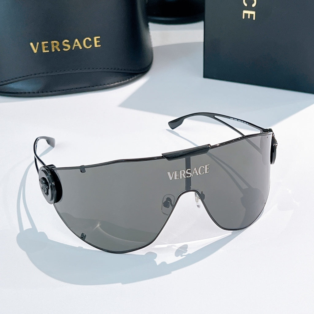 Shield sunglasses with dark gray lenses and slim black temples, round logo on side.