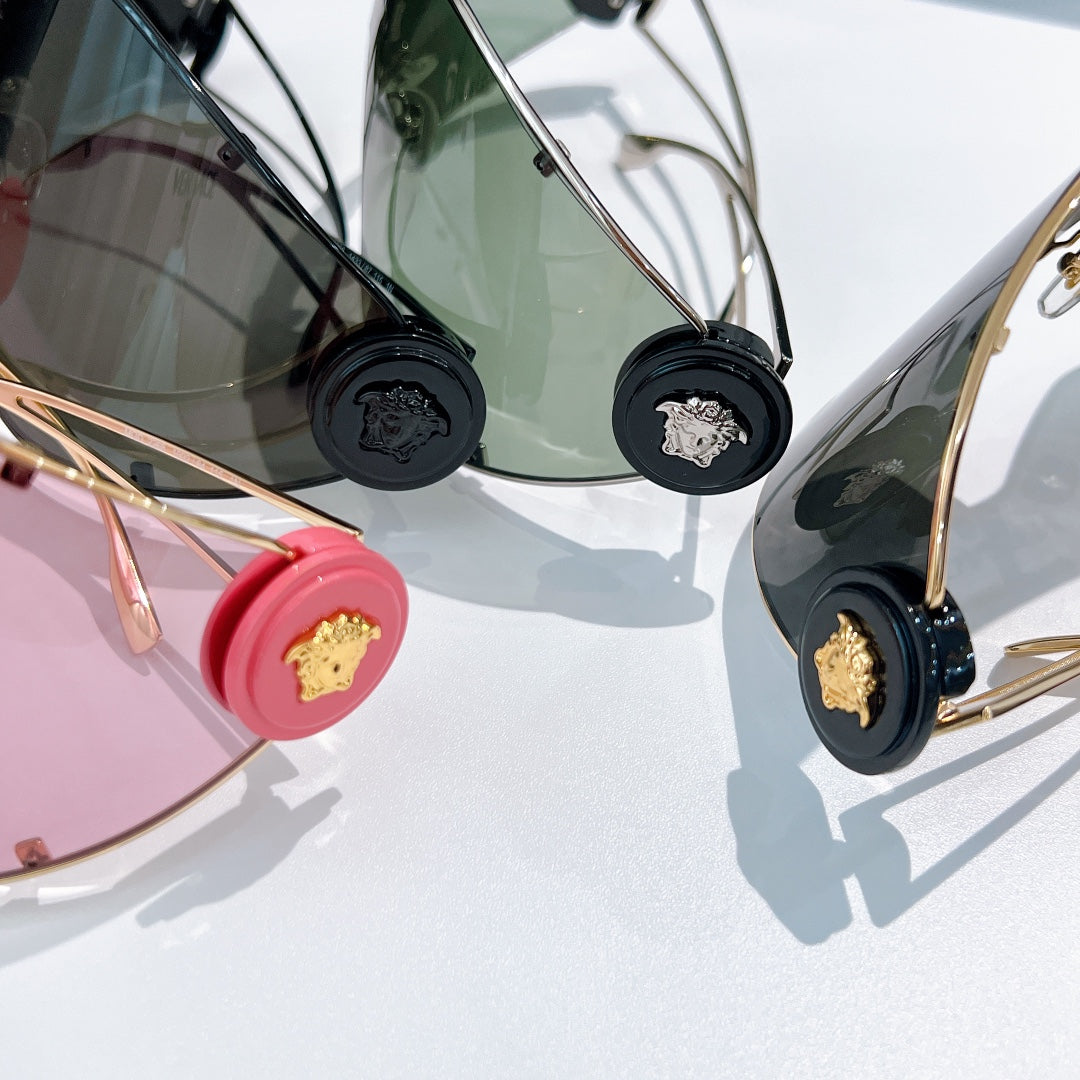 Close-up of shield sunglasses temples with black logo medallions and gold-tone accents.