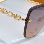 Gold chain temple sunglasses with dark frame tips and pink tinted lenses