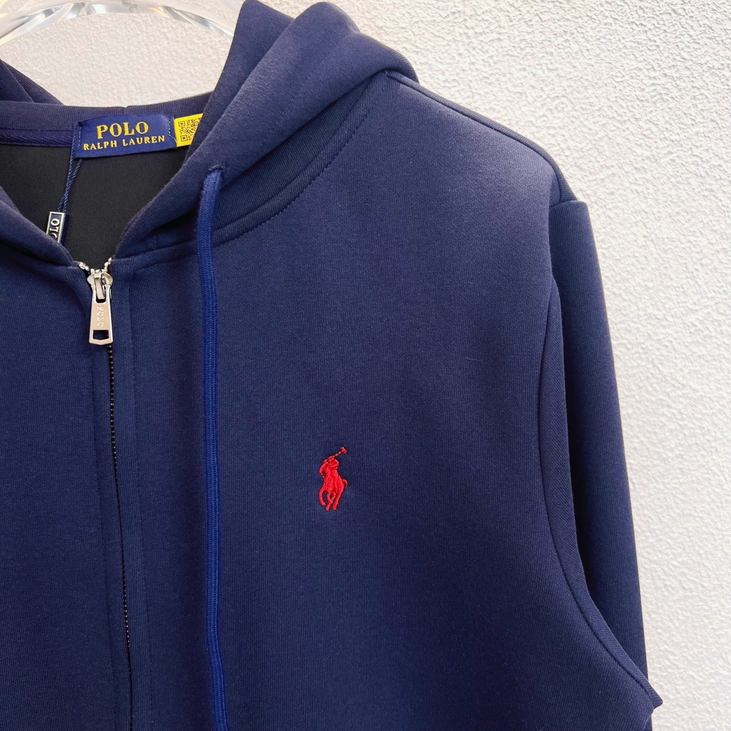 Navy zip-up hoodie close-up with red polo logo on chest