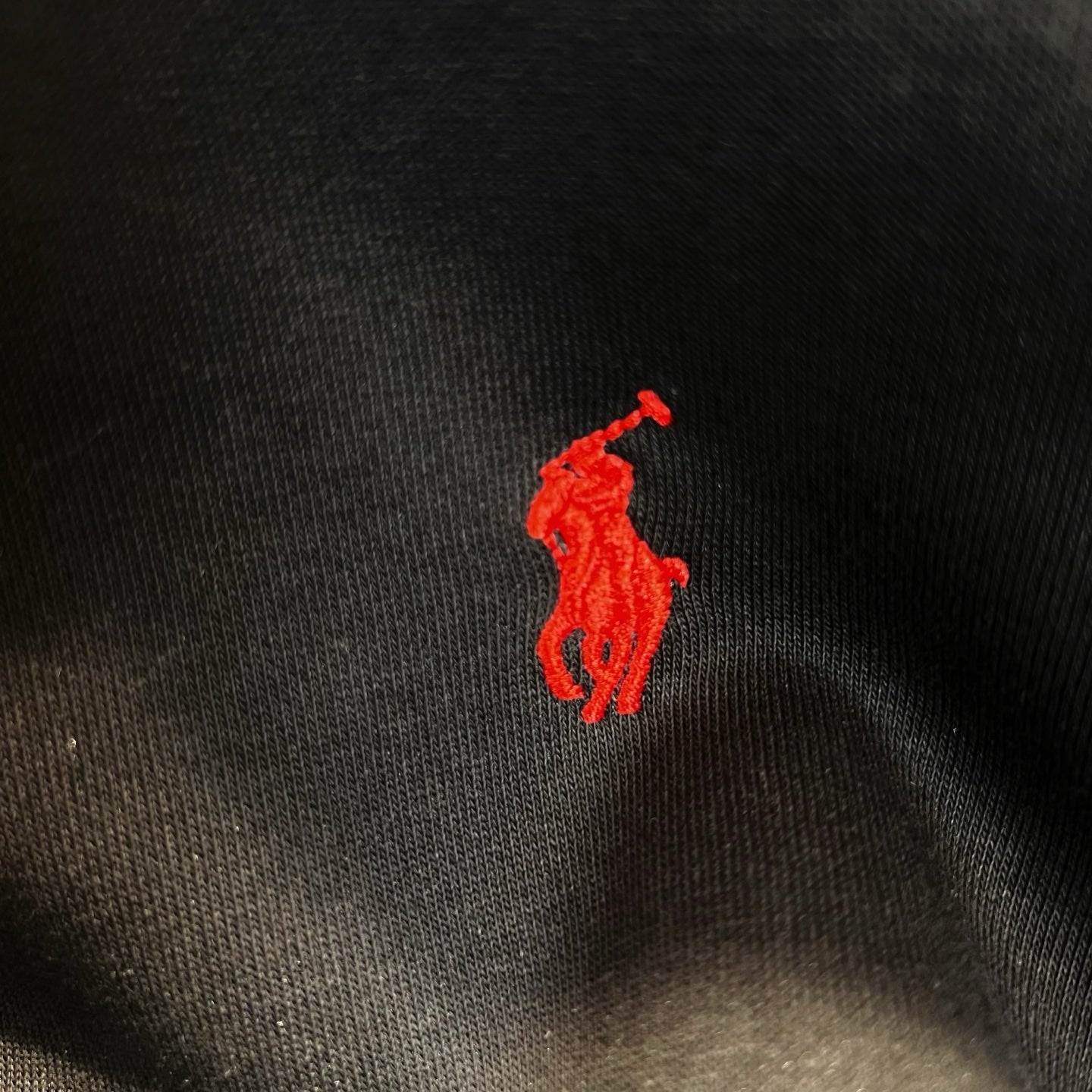 Red polo horse logo on dark fabric of a zip-up hoodie