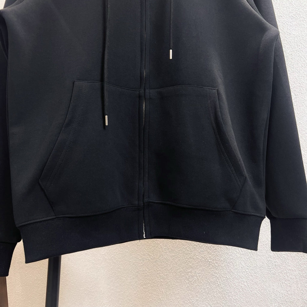Dark zip-up hoodie with kangaroo pocket and ribbed hem, visible metal zipper pulls