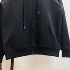 Dark zip-up hoodie with kangaroo pocket and ribbed hem, visible metal zipper pulls