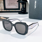 Dark gray sunglasses with smoke lenses and Prada logo on the side arm