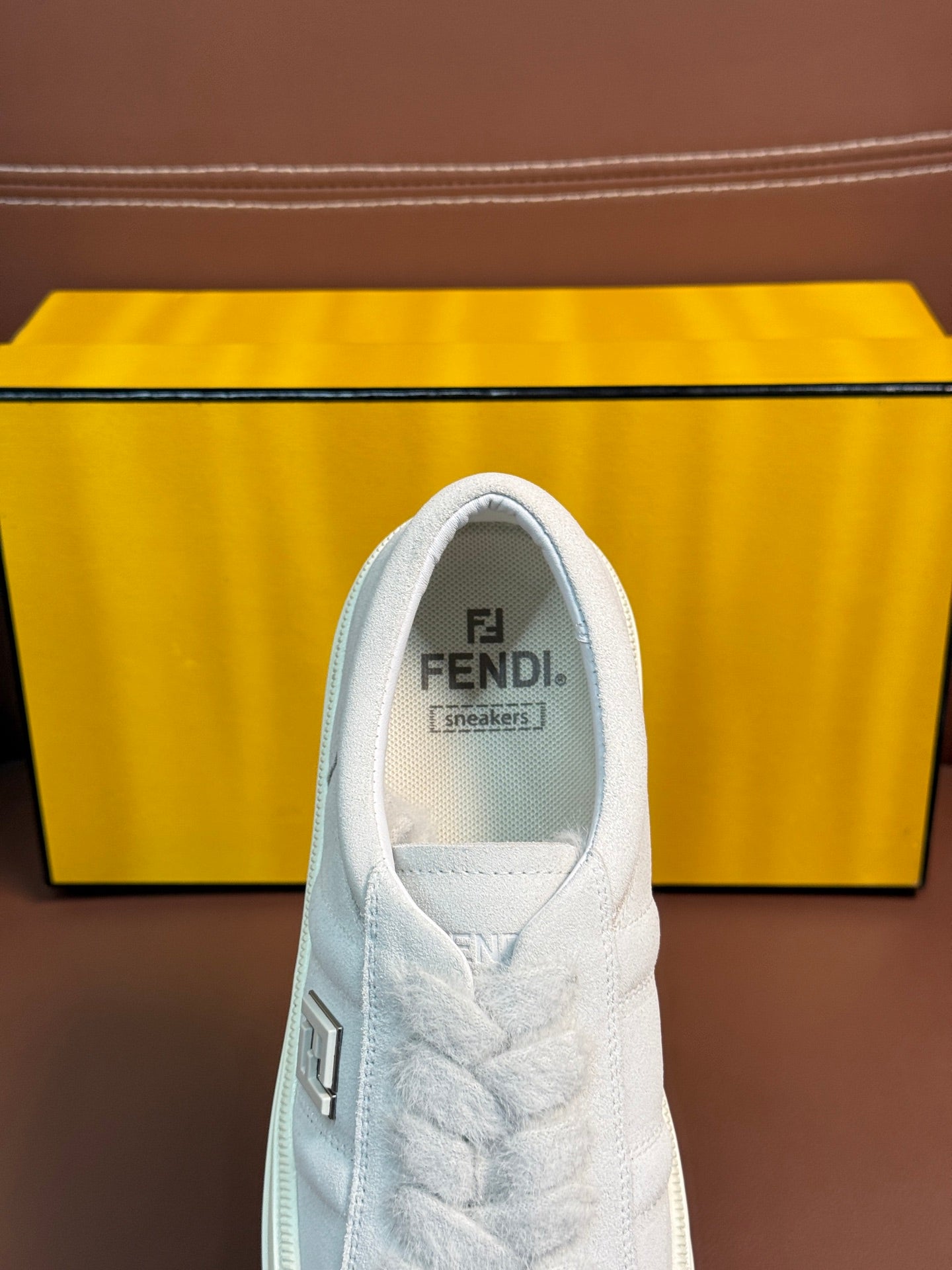White Fendi unisex sneaker, close-up of tongue with Fendi logo and lace detailing