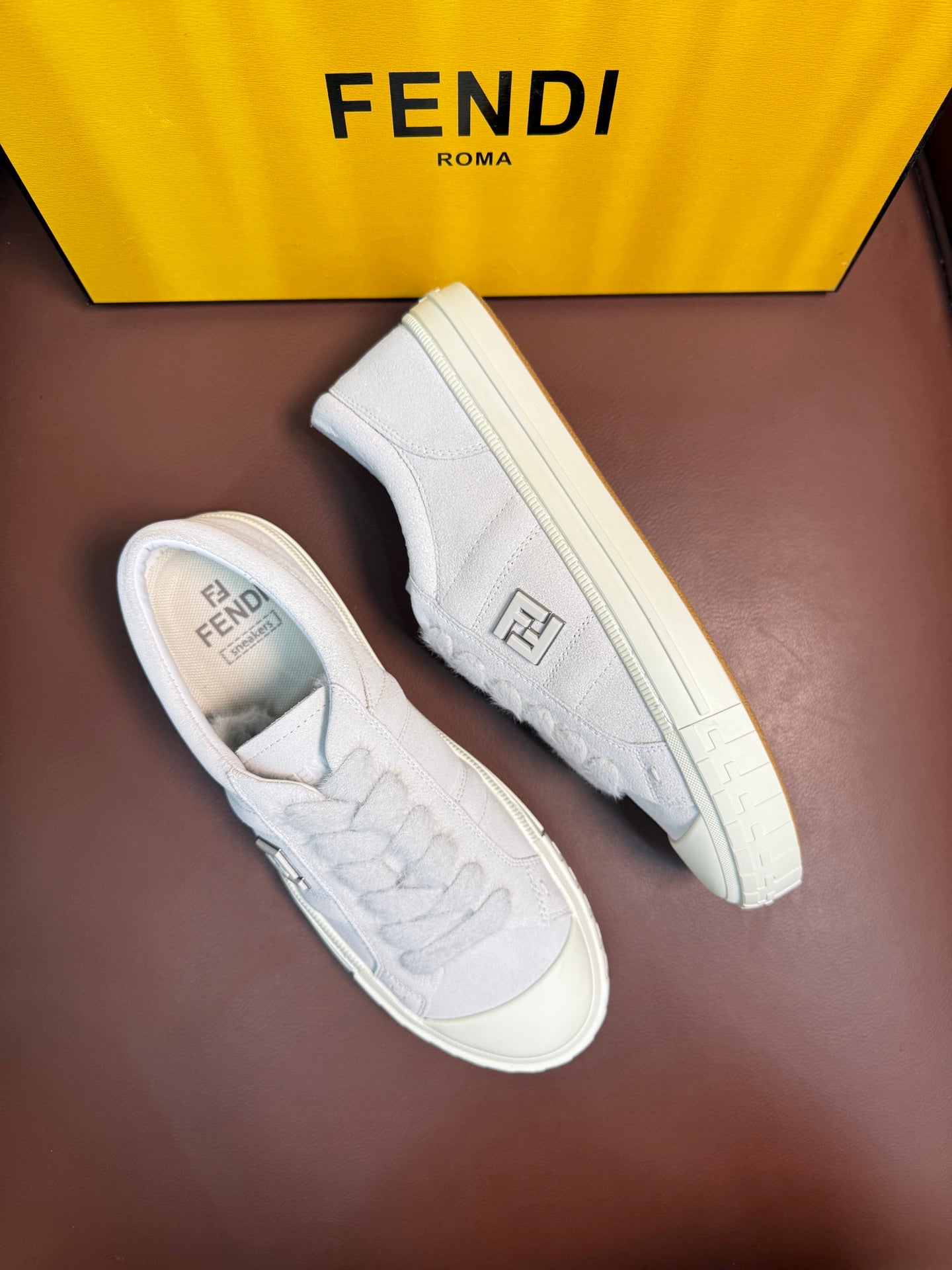 White Fendi unisex sneakers, angled side view with embroidered logo on the upper