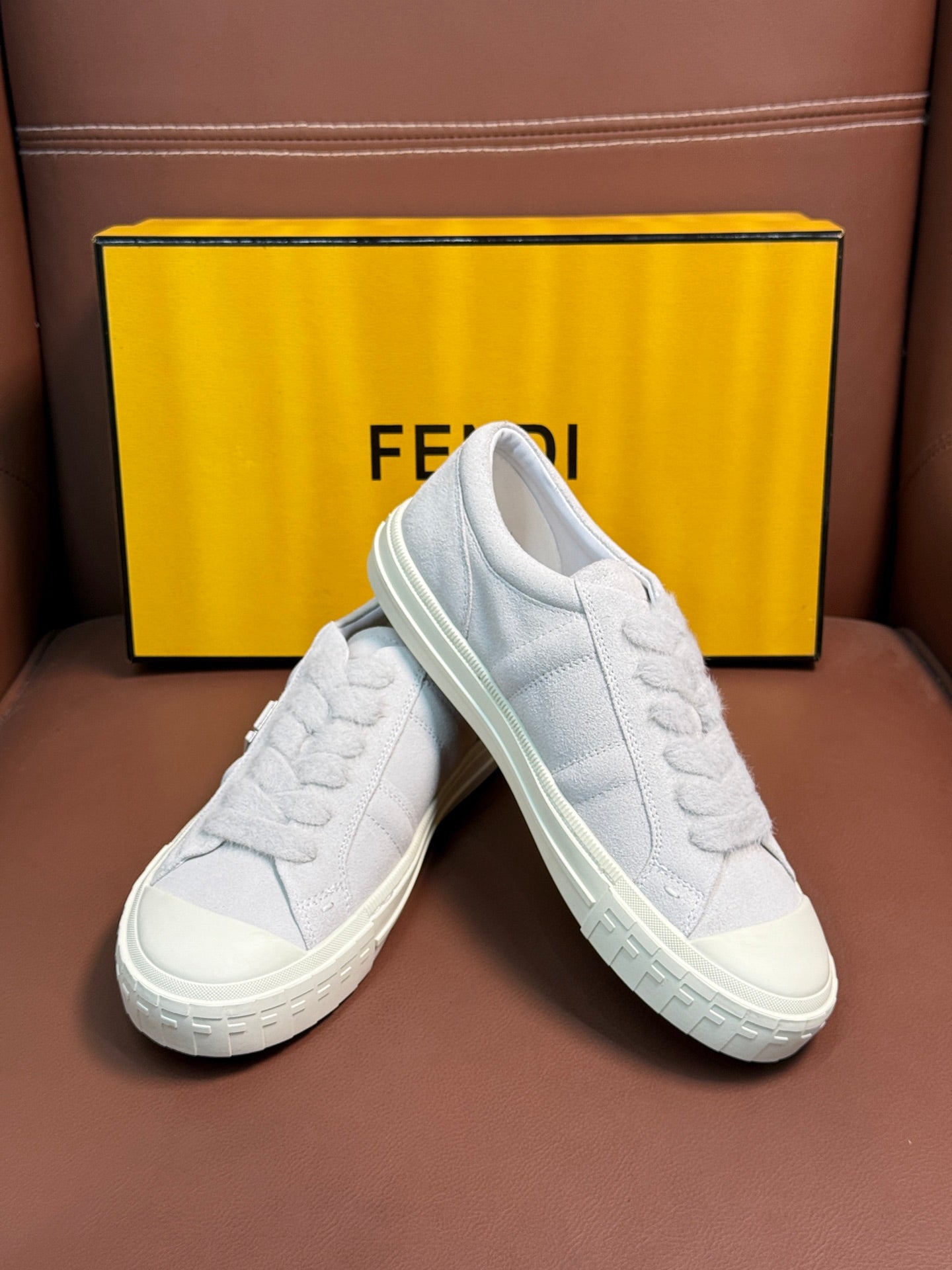 White Fendi unisex sneakers, pair at angle showing laces and chunky textured sole