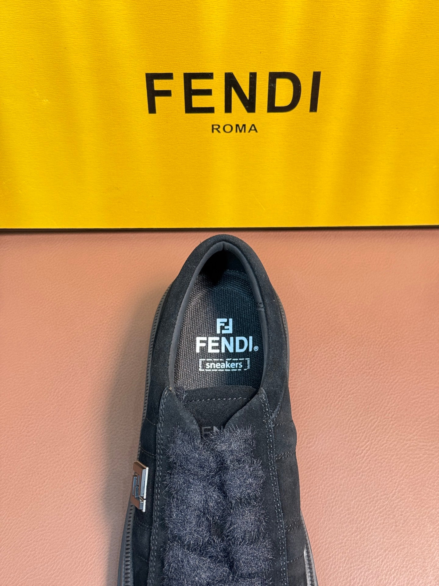 Fendi unisex sneaker interior view with dark suede upper and logo label