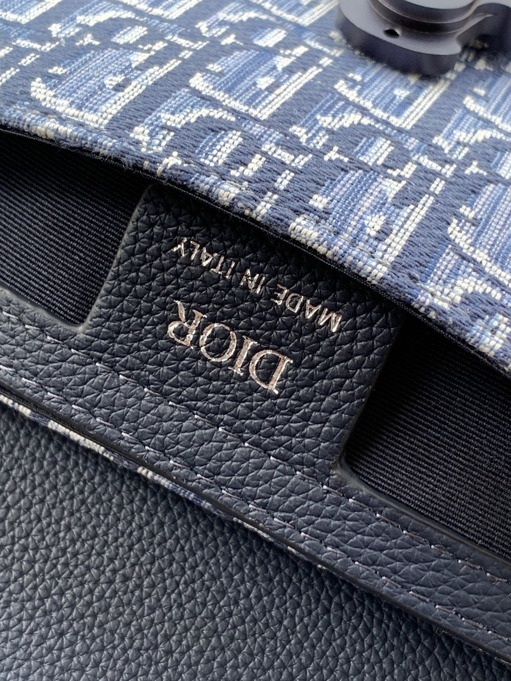 Dior logo embossed on textured navy leather bag flap