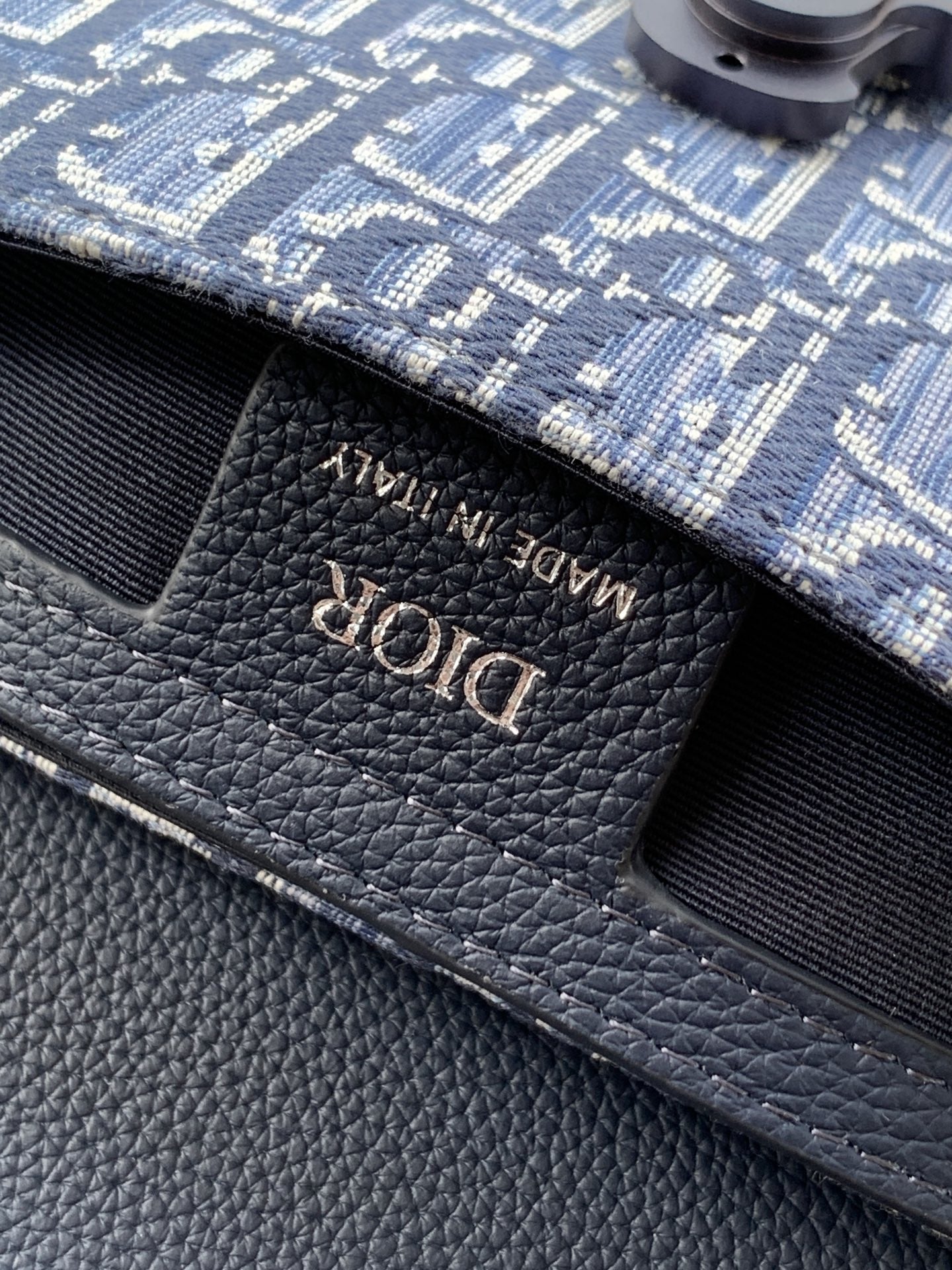 Dior logo embossed on textured navy leather bag flap
